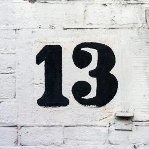 The number 13 is painted in black on a white brick wall, possibly in relation to 13 Reasons Why.