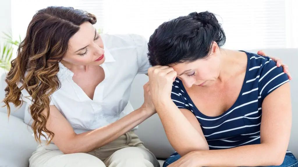 A woman is comforting another woman who appears distressed, possibly indicating a forgiveness process.