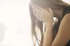 A person is sitting with their head in their hands, appearing upset or distressed.