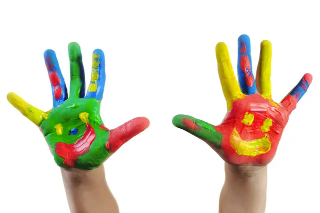 Two hands painted colorfully with smiley faces, symbolizing creativity and joy. Dreams for our children.