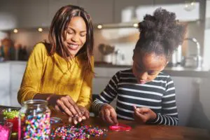 Two people enjoying a craft activity, sorting colorful beads together on a table.