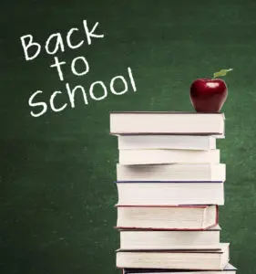 A stack of books with an apple on top, next to the phrase "Back to School" on a green chalkboard background.