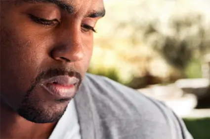 A person appears to be deep in thought or sad, with a blurred background, related to learning how to cope with grief.