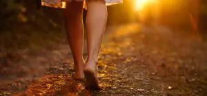 Barefoot person walking on a sunlit path, evoking a sense of tranquility and nurturing self-love.