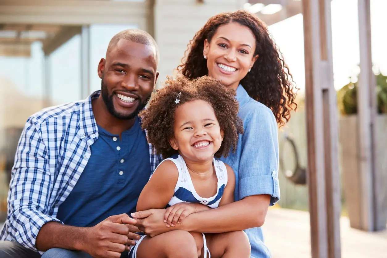 A smiling family is sitting together outdoors.