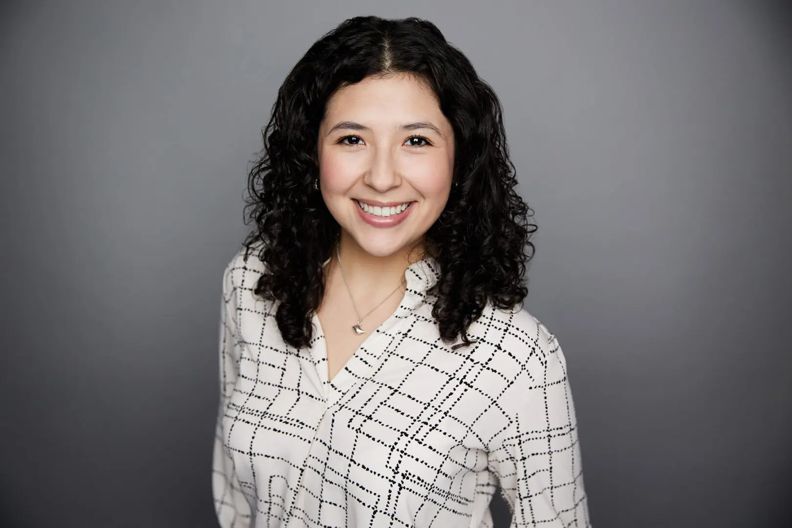 Smiling woman with curly hair and blouse.