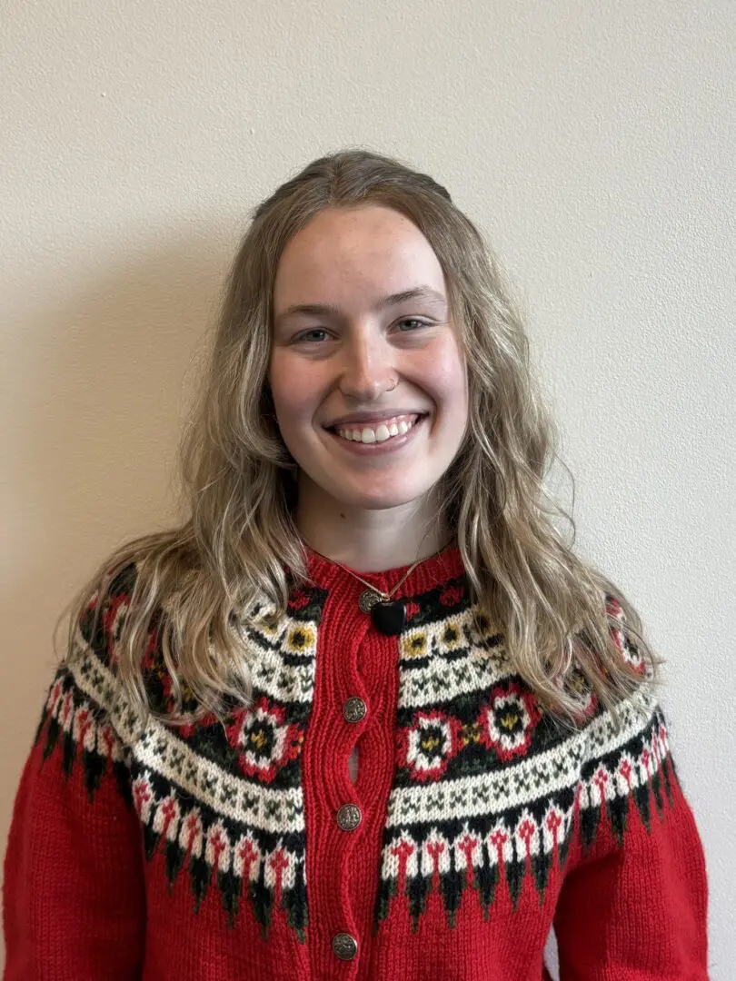 Smiling person wearing a patterned red sweater.