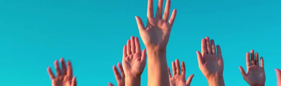 Multiple hands are raised against a clear blue sky, suggesting unity or participation.