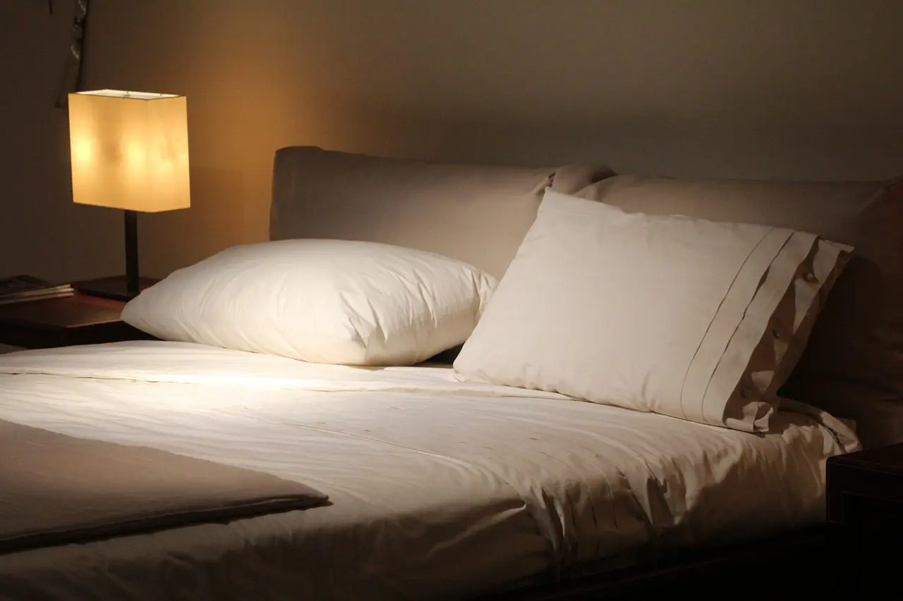 A cozy, softly lit bedroom with a neatly made bed and a bedside lamp.