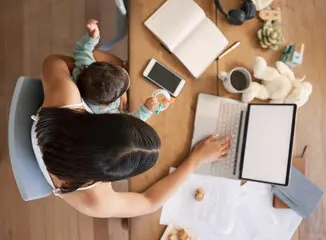 Parent multitasking with laptop and baby.