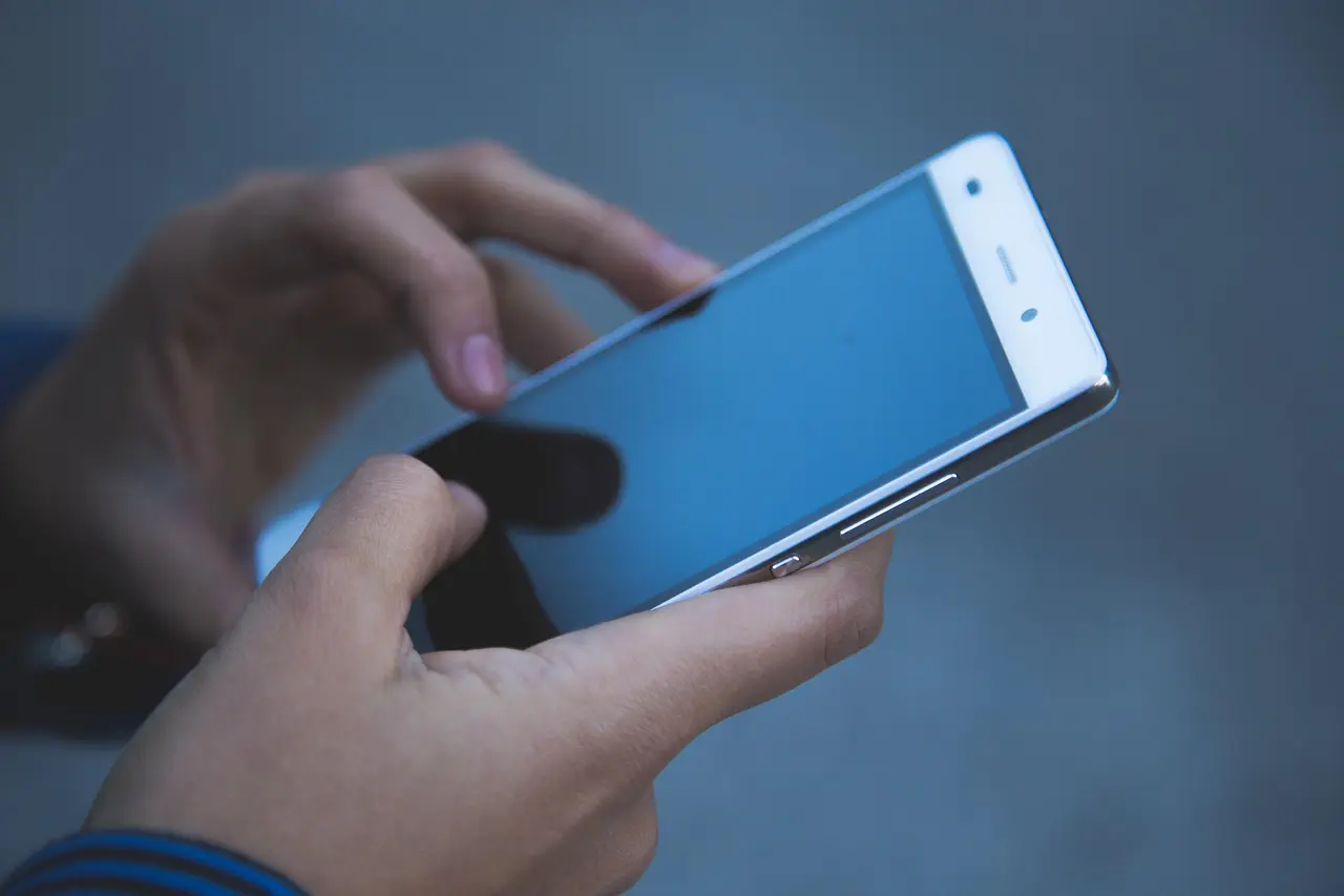 Person using a smartphone with a blank screen.