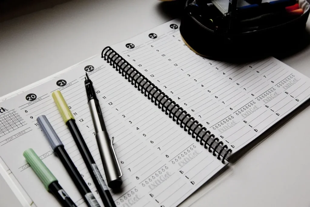 A planner with pens and markers is displayed, useful for staying organized.
