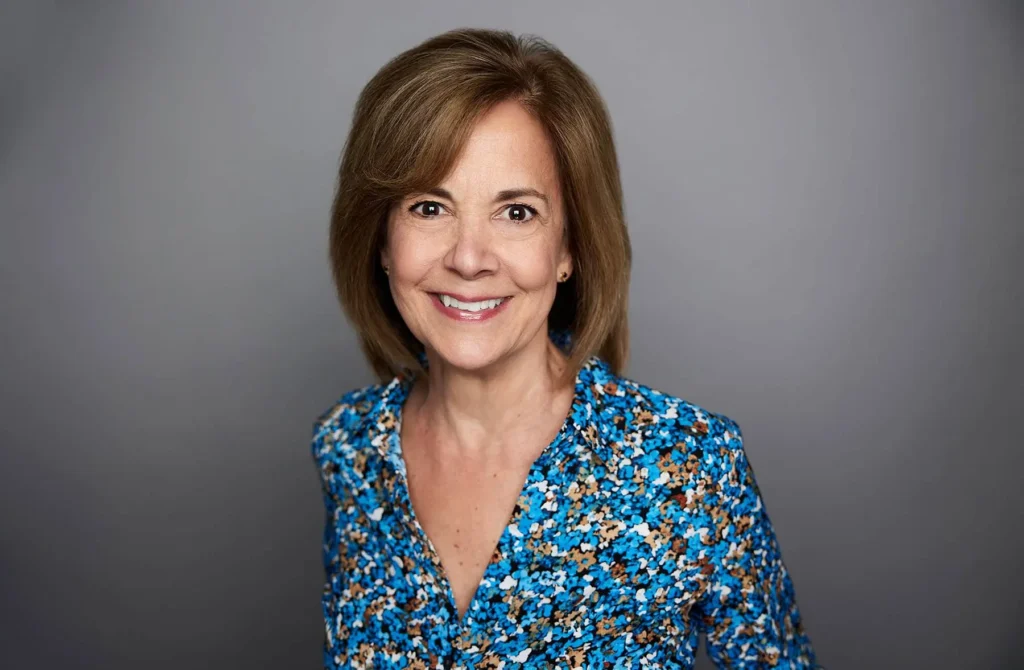Smiling woman in blue floral blouse.