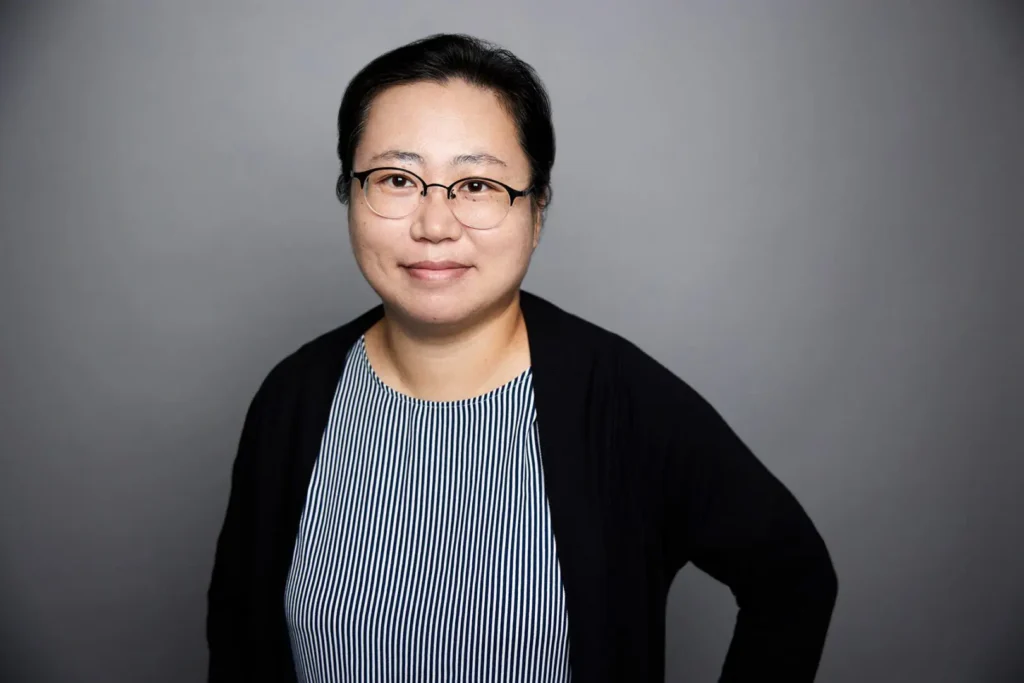 Smiling woman wearing glasses and striped shirt.