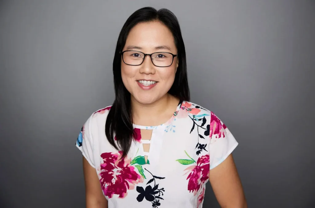 Smiling woman in floral blouse and glasses.