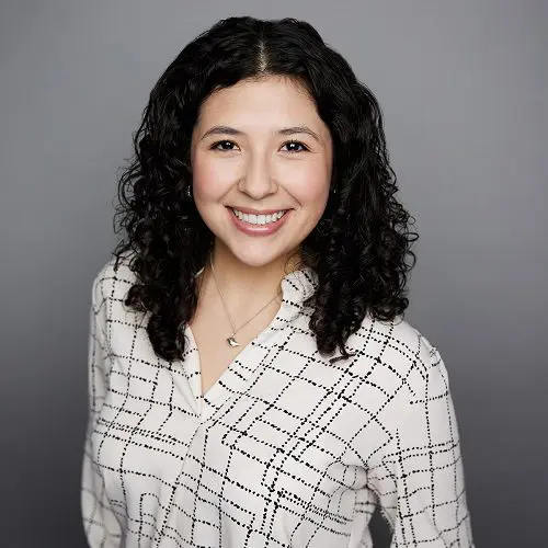 Smiling woman with curly hair, plaid shirt.