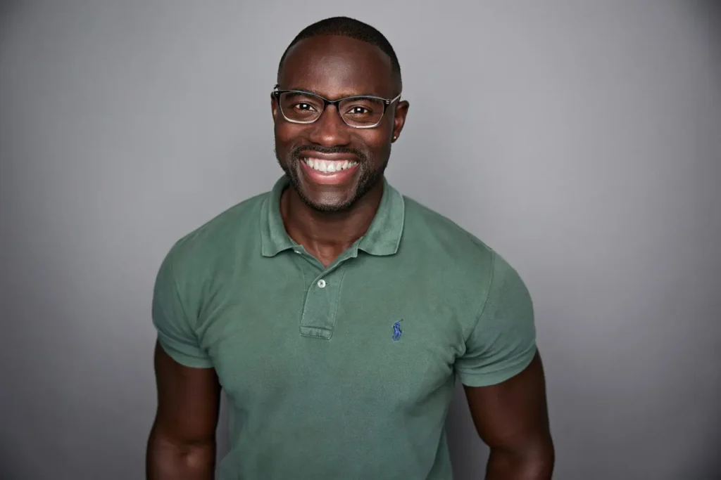 Smiling man wearing glasses and green shirt.