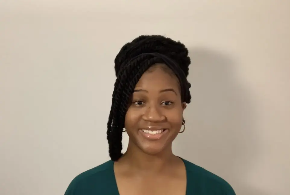 Smiling woman with braided hairstyle, green shirt.