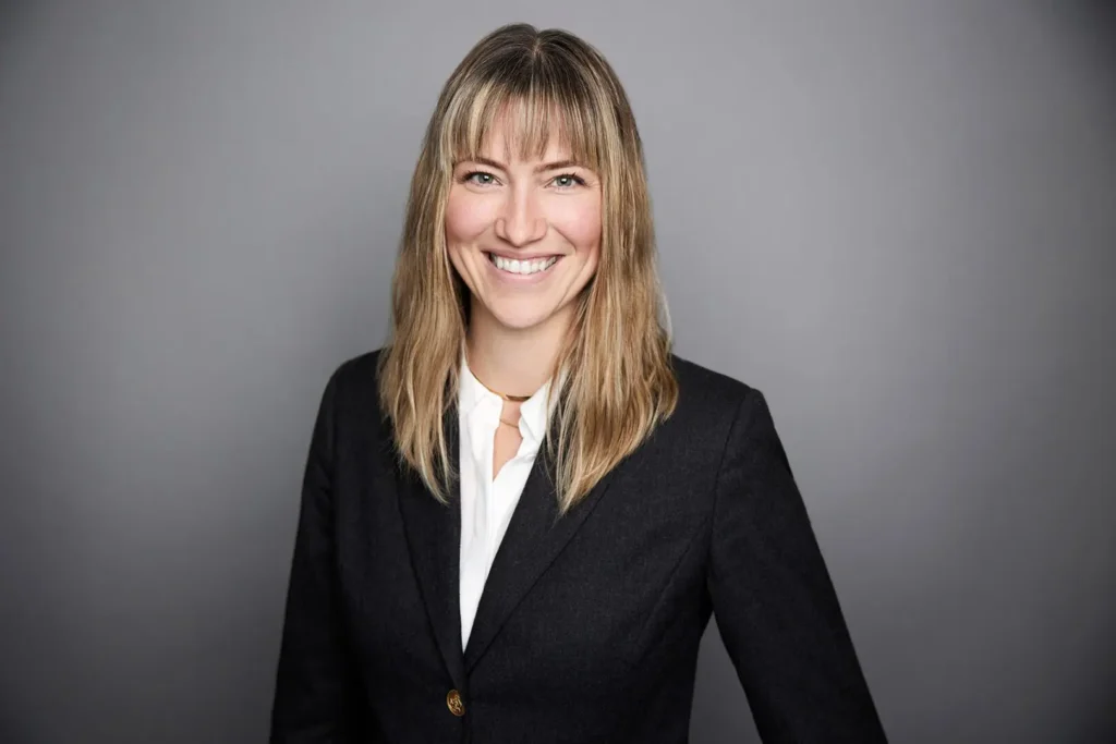 Smiling woman in professional attire, gray background.