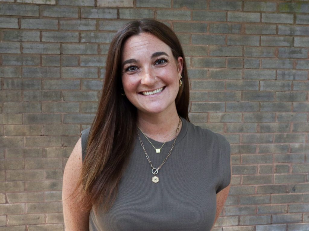 Smiling woman in front of brick wall.