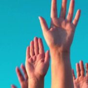 Hands raised against a clear blue sky.