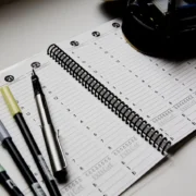 A planner with pens and markers is displayed, useful for staying organized.