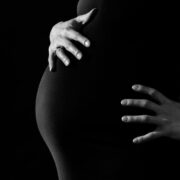 Pregnant woman holding belly in black dress.